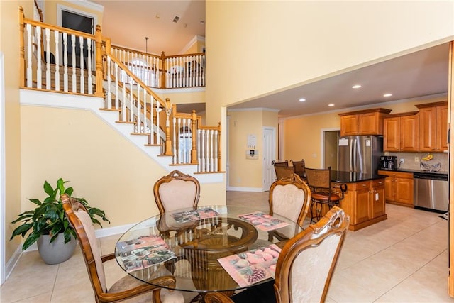 tiled dining area featuring ornamental molding, a high ceiling, and an inviting chandelier