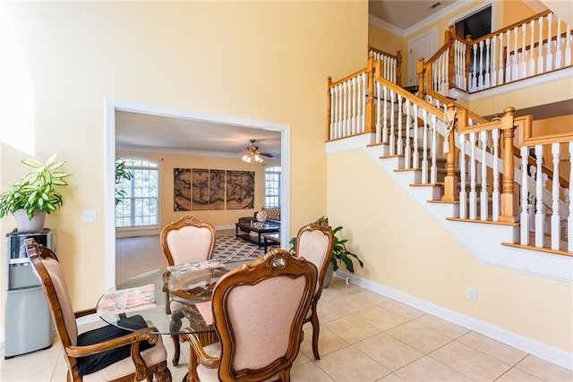 tiled dining space with crown molding, a towering ceiling, and ceiling fan