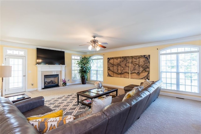 carpeted living room featuring ornamental molding, ceiling fan, and a wealth of natural light