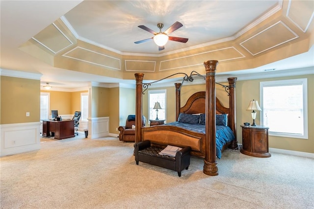 carpeted bedroom with crown molding, a tray ceiling, and ceiling fan