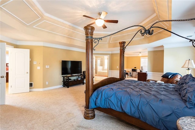 bedroom featuring ensuite bath, a tray ceiling, light carpet, ceiling fan, and crown molding