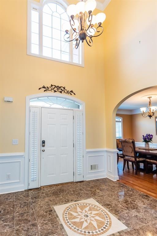 entryway featuring crown molding, a towering ceiling, and plenty of natural light