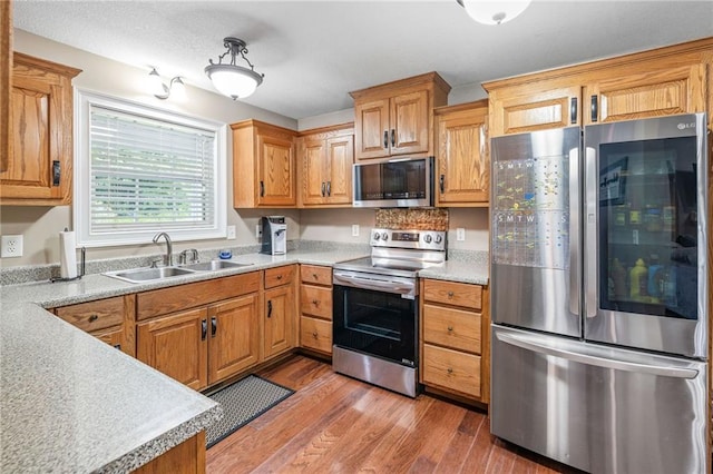 253 Grindstone Creek Dr, Clarkesville, GA 30523 - kitchen featuring appliances with stainless steel finishes, a sink, light wood-type flooring, light countertops, and brown cabinetry