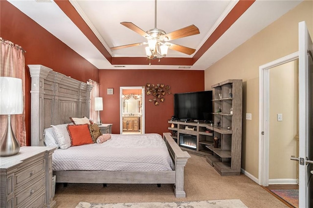 carpeted bedroom featuring a ceiling fan, visible vents, a raised ceiling, baseboards, and ensuite bathroom