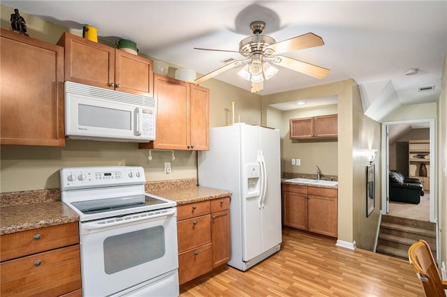 kitchen featuring brown cabinetry, a ceiling fan, white appliances, light wood-type flooring, and a sink