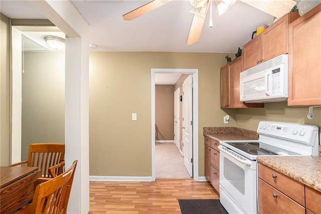 kitchen with light wood-style floors, a ceiling fan, baseboards, and white appliances