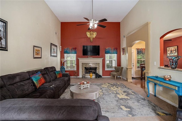 living room featuring carpet floors, a ceiling fan, arched walkways, and a high ceiling