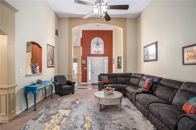 living area featuring visible vents, baseboards, a high ceiling, carpet, and ceiling fan with notable chandelier