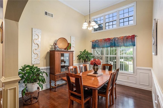 dining space with visible vents, crown molding, a wainscoted wall, a chandelier, and dark wood finished floors