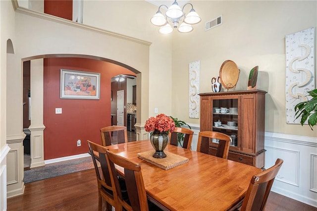 dining space with an inviting chandelier, arched walkways, dark wood-style floors, and visible vents