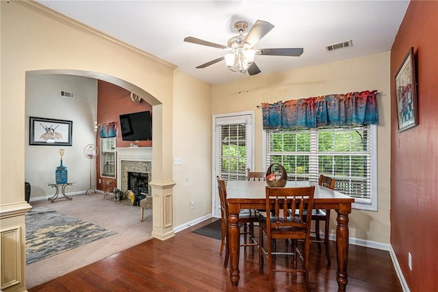 dining area featuring baseboards, ceiling fan, a fireplace, and visible vents