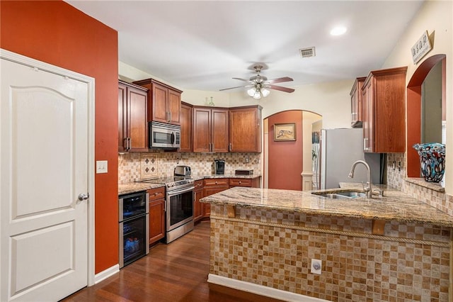 kitchen with visible vents, a sink, dark wood-style flooring, arched walkways, and stainless steel appliances