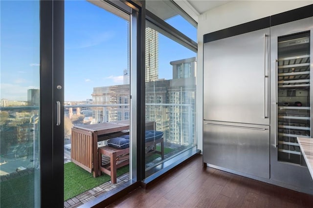 doorway to outside with a view of city, floor to ceiling windows, and wood finished floors