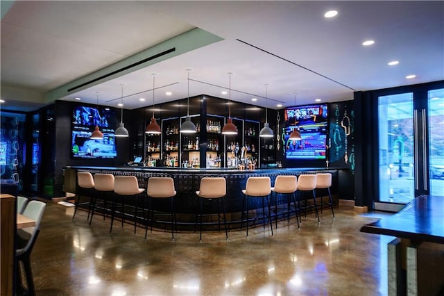 bar with concrete flooring, recessed lighting, decorative light fixtures, and a bar