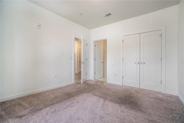 unfurnished bedroom with visible vents, carpet floors, baseboards, and a closet