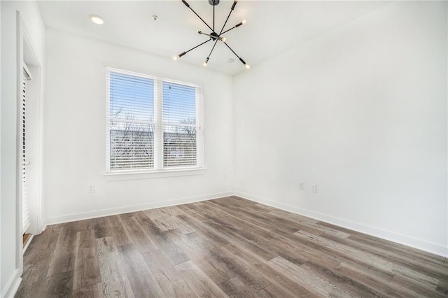 unfurnished room featuring recessed lighting, baseboards, an inviting chandelier, and wood finished floors