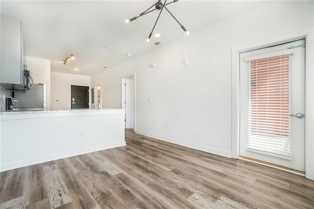 unfurnished living room with wood finished floors, baseboards, and a sink