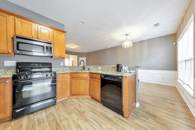 kitchen featuring black appliances, light wood-type flooring, kitchen peninsula, and light stone counters