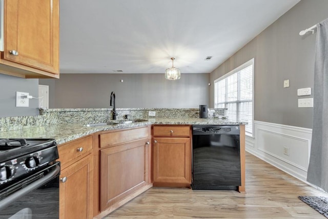 kitchen with light stone counters, sink, black appliances, and light hardwood / wood-style flooring