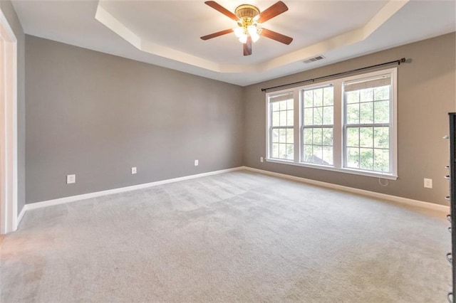 carpeted empty room with a tray ceiling and ceiling fan