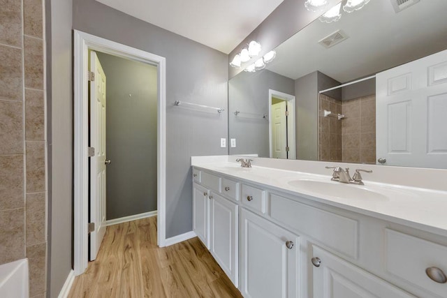 bathroom featuring tiled shower, hardwood / wood-style floors, and vanity