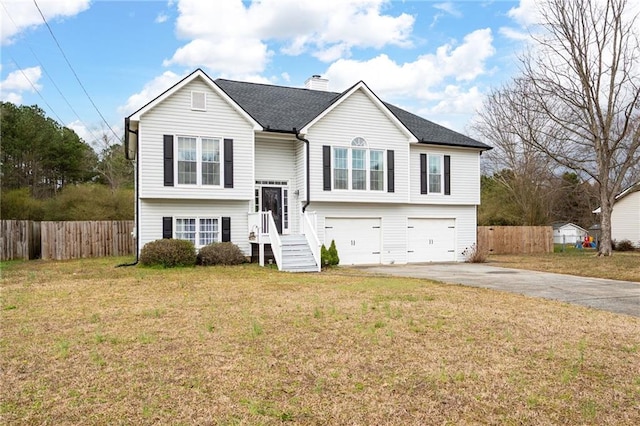 split foyer home with a garage, driveway, a chimney, and fence