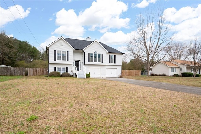 raised ranch featuring driveway, a garage, fence, and a front yard