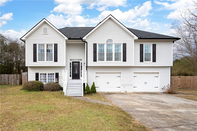 bi-level home featuring an attached garage, fence, driveway, roof with shingles, and a front yard