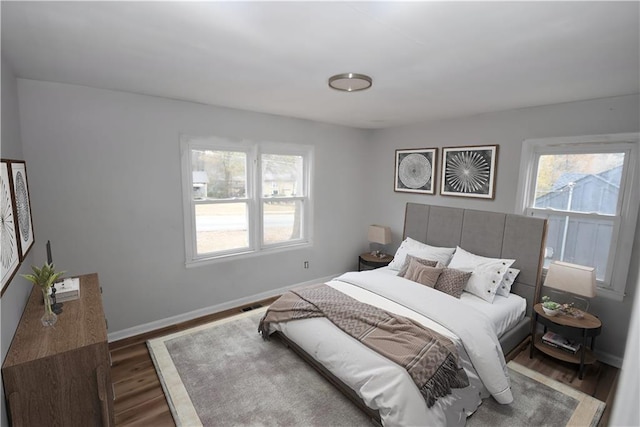 bedroom with multiple windows and dark hardwood / wood-style floors