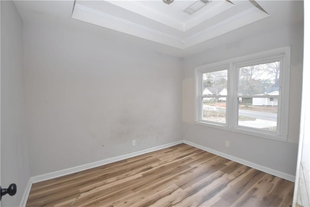 spare room with hardwood / wood-style flooring, crown molding, and a tray ceiling