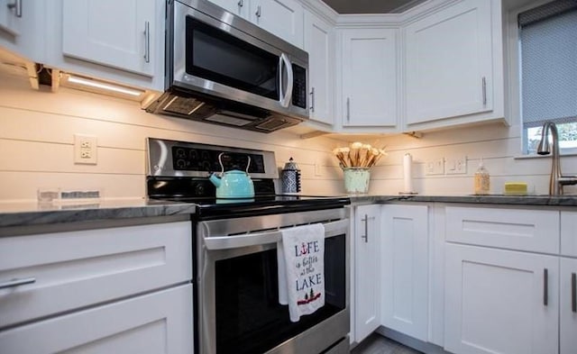 kitchen featuring appliances with stainless steel finishes, sink, white cabinets, and decorative backsplash