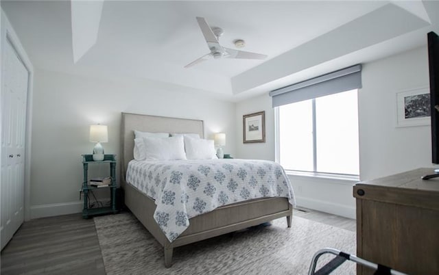 bedroom featuring hardwood / wood-style flooring, a raised ceiling, and ceiling fan