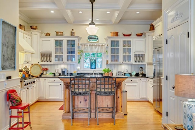 kitchen with light hardwood / wood-style floors, coffered ceiling, and a kitchen island