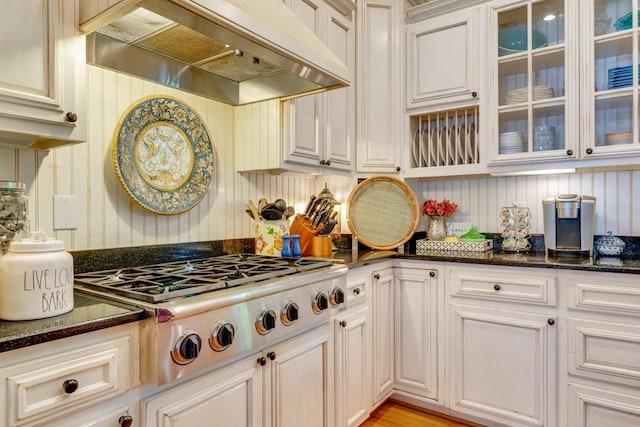 kitchen with white cabinetry, dark stone counters, premium range hood, and stainless steel gas stovetop