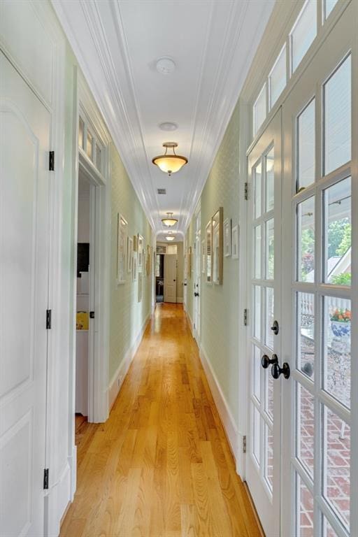 hall with crown molding, light hardwood / wood-style flooring, and french doors