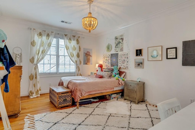 bedroom with crown molding, a chandelier, and light hardwood / wood-style floors