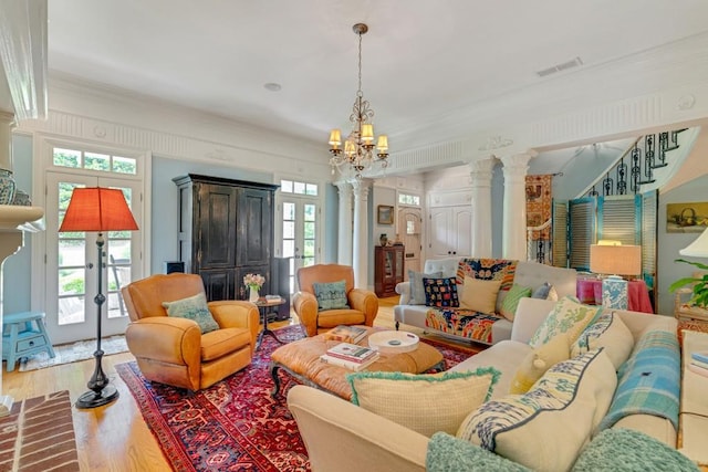 living room with ornate columns, a wealth of natural light, hardwood / wood-style flooring, and a chandelier