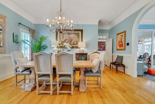 dining space with an inviting chandelier, crown molding, and light wood-type flooring