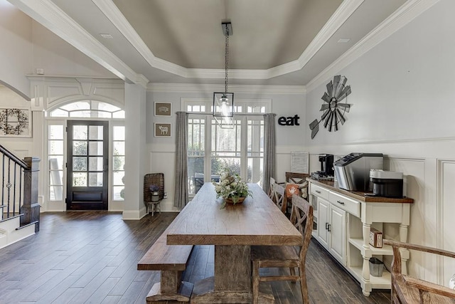 dining room featuring a raised ceiling, ornamental molding, dark hardwood / wood-style floors, and a notable chandelier