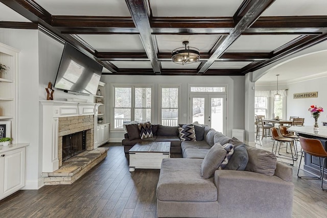 living room featuring a brick fireplace, coffered ceiling, beamed ceiling, dark hardwood / wood-style floors, and french doors