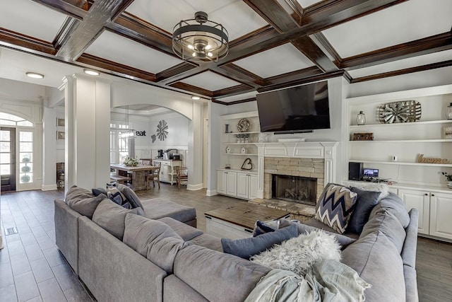 living room with a fireplace, beam ceiling, coffered ceiling, ornamental molding, and built in features