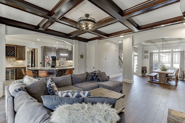 living room with dark hardwood / wood-style flooring, beamed ceiling, ornamental molding, and coffered ceiling