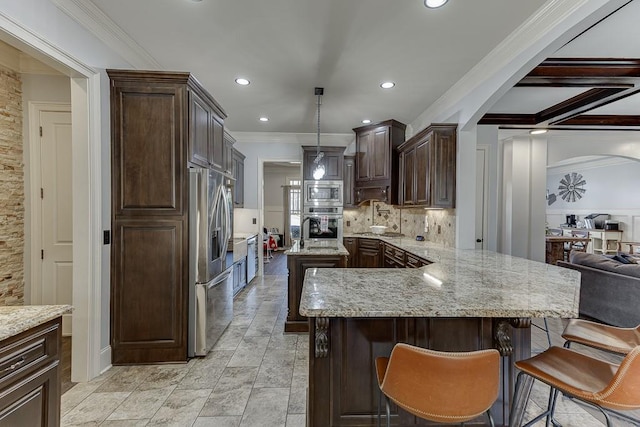 kitchen featuring dark brown cabinets, stainless steel appliances, pendant lighting, ornamental molding, and a kitchen bar