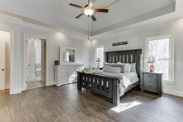 bedroom with dark wood-type flooring, ensuite bath, ceiling fan, a raised ceiling, and crown molding