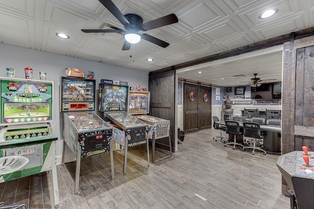 game room featuring hardwood / wood-style floors, ceiling fan, and a barn door