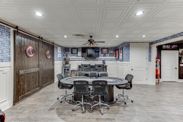 dining space featuring ceiling fan, a barn door, and light hardwood / wood-style floors