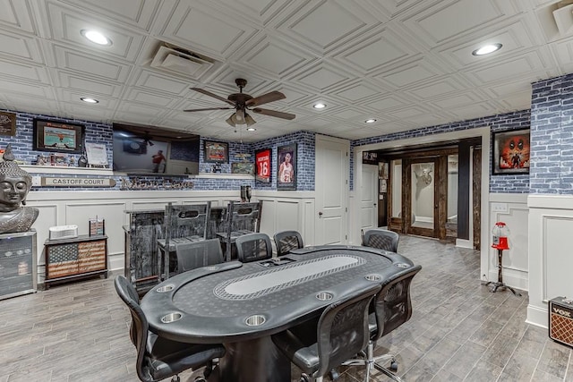 recreation room featuring ceiling fan, light wood-type flooring, and bar area