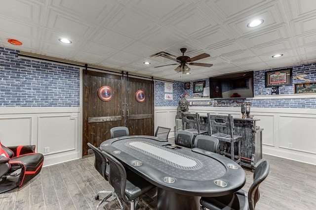 game room featuring ceiling fan, a barn door, and light hardwood / wood-style floors