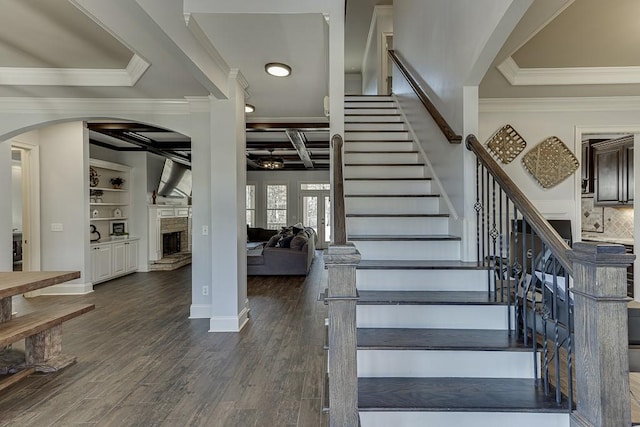 staircase featuring wood-type flooring, built in features, and ornamental molding