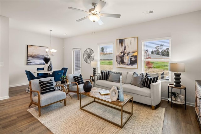 living room with ceiling fan with notable chandelier and dark hardwood / wood-style floors